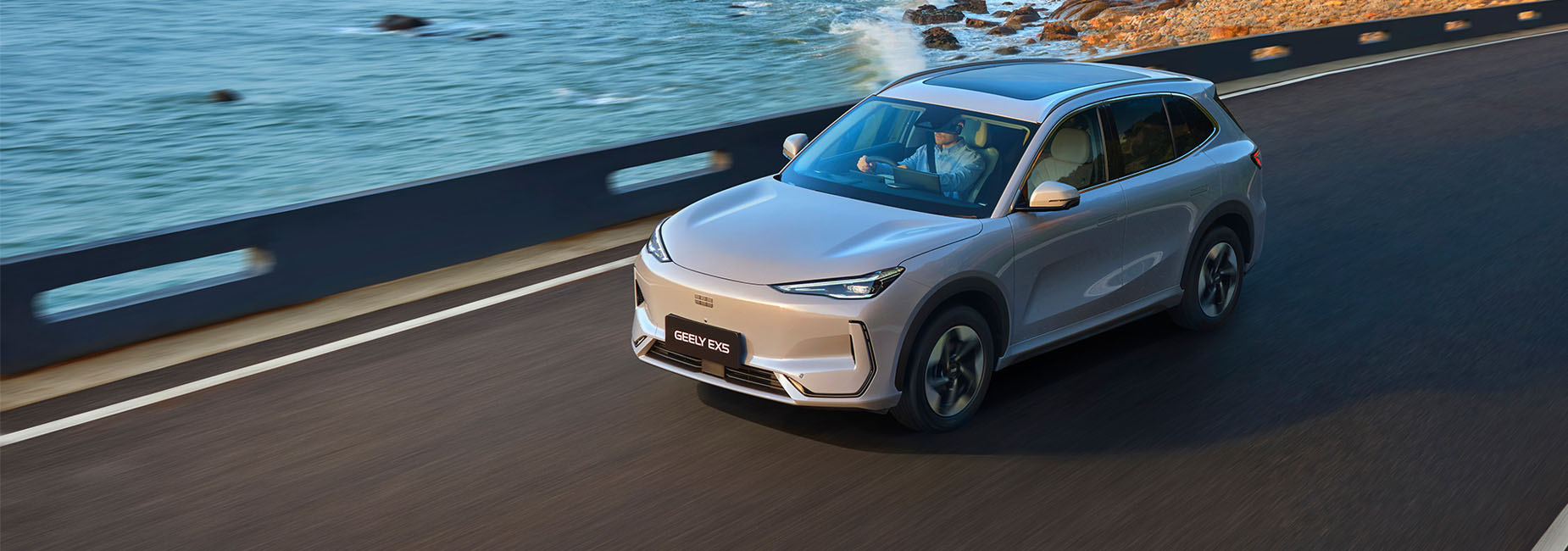 A Geely EX-5 driving on a coastal road