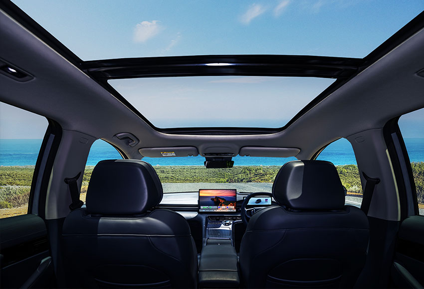 Interior of a Geely EX5 with a sunroof parked by the ocean