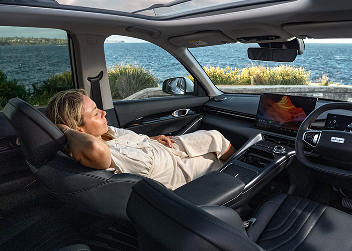 A woman laying in the passenger seat of a Geely SUV