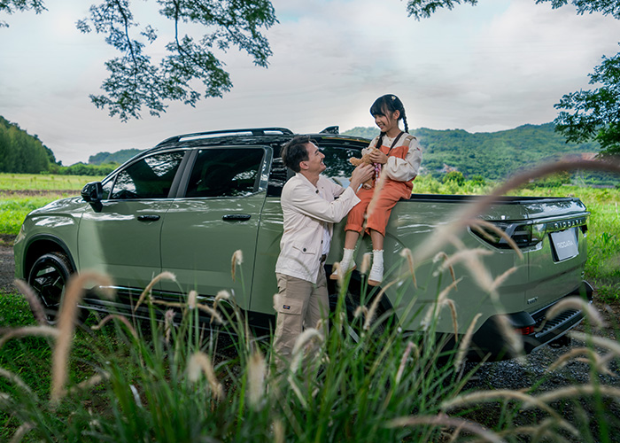 A daugther sitting on the tray of a ute while her father talks to her