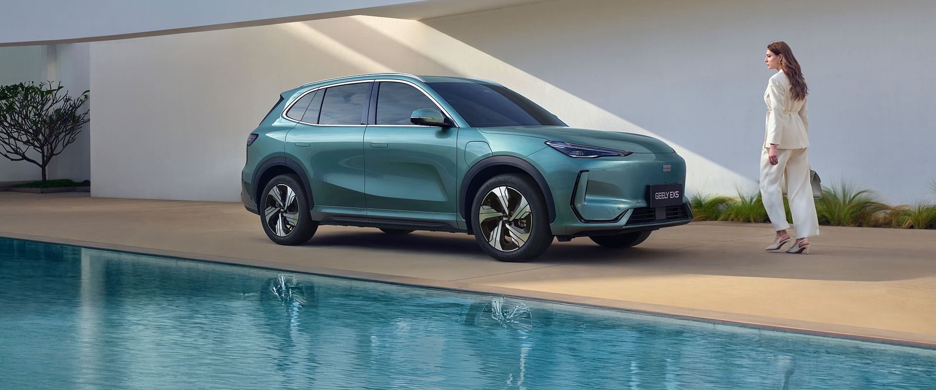 A woman walking up to a Geely SUV next to a pool